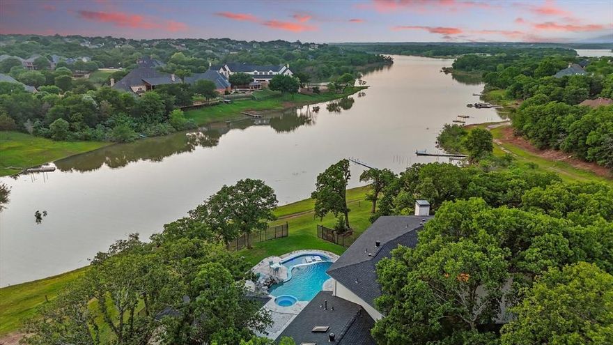 Rare opportunities to own true lakefront property in Highland Shores rarely come to market—especially on one of the neighborhood’s largest and most private homesites. Set on a 1.46-acre cul-de-sac lot with sweeping water views and unforgettable sunsets, this custom-built residence offers a lifestyle that blends nature, luxury, and resort-style outdoor living.

Tucked beneath a canopy of mature trees, the property offers exceptional privacy while showcasing panoramic lake views from multiple outdoor living areas. The backyard feels like a private retreat, featuring a resort-style infinity pool with Baja tanning ledge, intricate tile work, and unobstructed water views.

Designed for year-round entertaining, the outdoor oasis includes an expansive covered patio with a see-thru fireplace, built-in heaters, pizza oven, and full outdoor kitchen, along with a newly built deck and **permitted lake pump** on the property for convenience.

Inside, the thoughtfully designed floor plan balances comfort and sophistication. The downstairs primary suite offers private patio access and a spa-like bath. The entertainer’s kitchen features an induction cooktop, stainless appliances, granite counters and updated backsplash, open to the large living room with full bar. A guest suite with full bath is also on the main level, while upstairs are two oversized bedrooms with private en-suites and balconies, plus a versatile loft with sauna—ideal for a home gym or easily convertible into a game room.

An oversized three-car garage and extensive mechanical and structural upgrades add confidence for the next owner, including a new roof (2024), balcony with cable railing (2024), HVAC systems (2021 & 2022), water heater (2025), pool renovation with infinity feature (2020), and outdoor living expansion (2020-2021).

With its rare lakefront setting, large private lot, and exceptional outdoor living, this Highland Shores property offers one of the community’s most unique opportunities.