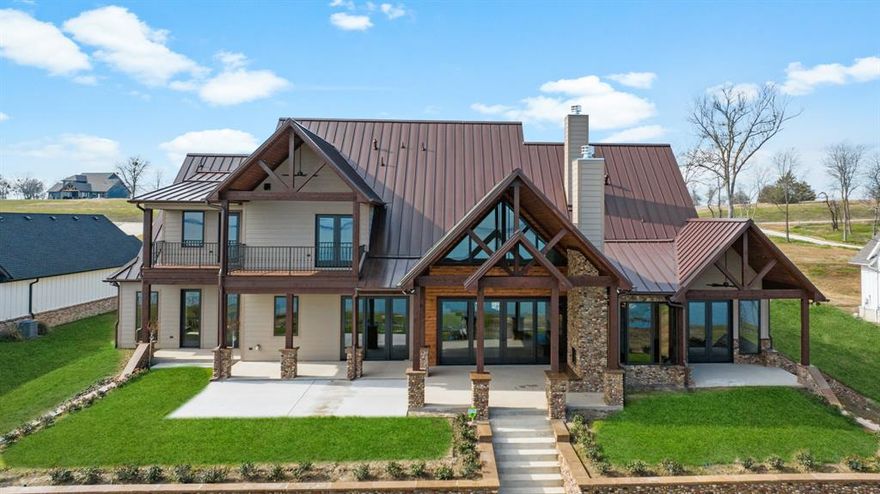 ***Generous builder incentives available - options can include 3 years of paid HOA dues, interest rate buy-down or closing costs assistance and a boathouse allowance with acceptable offer. Incredible value—don't miss this opportunity to save thousands and have added peace of mind! *** This new construction home has been built to create not just a home, but an experience. As you enter you're greeted by breathtaking lake views through the wall-to-wall Pella doors & windows. The great room features 20ft ceilings & a stone fireplace with marble surround. An open floor plan transitions into a dining room & a gourmet chef's kitchen with dry bar. Culinary dreams come true with a large quartz island, top-of-the-line appliances, custom cabinetry, & a one-of-a-kind wine grotto with wine cellar holding up to 100 bottles. The home has 2 luxurious primary suites, 4 additional bedrooms, multiple ensuite baths & a 2nd upstairs living area. Multiple patios & balconies, plus an outdoor fireplace are designed to maximize the panoramic waterfront views. Fully integrated security, wi-fi, speakers, sonos-ready wiring are move in ready. With 116ft of shoreline, this property offers the ultimate combination of luxurious living and prime waterfront access for a future boat house. Make sure to check the documents for the extensive list of warranties that the builder is offering!