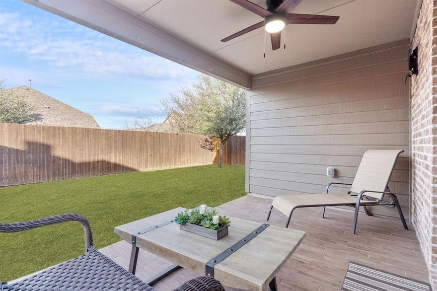 Beautiful single-story brick home accented with stone details, ideally located in the Fossil Creek at Westridge community in McKinney. A landscaped front yard welcomes you to a covered brick porch and a wood front door with frosted glass detailing, complete with a Ring doorbell camera. Upon entry, engineered wood floors extend throughout the home, complemented by abundant natural light and a vaulted 9-foot ceiling. The spacious living room features a ceramic wood-burning fireplace with gas starter, creating a cozy focal point, and includes a mounted TV. The pristine galley-style kitchen offers tile flooring, dark walnut cabinets with crown molding, leathered granite countertops, mosaic tile backsplash, an undermount dual sink, bar-height peninsula seating, Frigidaire stainless steel appliances, and an oversized walk-in pantry. The private primary suite features wood floors, serene backyard views from two windows, a vaulted ceiling with fan, and French doors to the en suite bathroom. The primary bath includes a walnut dual vanity with upgraded granite countertops and undermount sinks, updated walnut-framed mirrors, elegant glass light fixtures, a soaking tub, separate tiled shower, private water closet, and a generous walk-in closet with built-in shelving. Two secondary bedrooms feature wood floors, vaulted ceilings with fans, and ample closet space. A full bath offers a walnut vanity with upgraded granite countertop, updated mirror, and tub-shower combo. Additional amenities include upgraded arched interior doors, security system wiring, Honeywell thermostat, upgraded remote sprinkler system, transferable home warranty through May 2027, a 2-car garage, and recent updates including a 2023 roof, fresh paint, mirrors in both bathrooms, and patio tile. Enjoy the covered back porch with new tile flooring and ceiling fan, a spacious fenced yard, and access to the community pool just a one-minute walk away. Zoned for Prosper ISD.