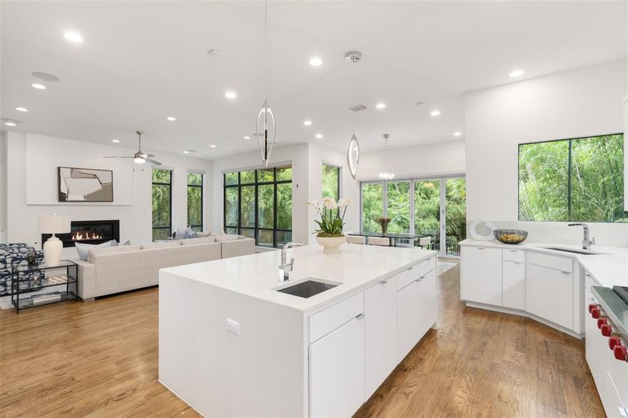 Discover the epitome of secluded luxury in Lakewood with this stunning contemporary home, featuring expansive walls of windows that frame breathtaking views of a heated infinity-edge pool and a serene creek surrounded by a bamboo forest. Nestled in nature yet incredibly convenient, this home is just steps away from the award-winning Lakewood Elementary, and only minutes from White Rock Lake, Lakewood Country Club, and the charming Lakewood Shopping Center. Designed for both grand entertaining and comfortable everyday living, the functional floor plan includes a downstairs exercise room with a Harvia Claro Sauna, offering the flexibility to be converted into a 5th bedroom. The open-concept layout bathes the home in natural light, while sophisticated design elements such as a floating metal staircase, an elegant gas fireplace, and stylish designer lighting elevate the aesthetic throughout. The chef-inspired kitchen is equipped with top-tier Wolf, Sub-Zero, and Asko appliances, as well as a wine and beverage fridge for ultimate convenience. The adjacent bar area boasts custom cabinetry, two mini-fridges, and a striking floor-to-ceiling metal wine rack, perfect for both everyday use and special occasions. Upstairs, the luxurious owner’s retreat includes a spacious primary suite with private balcony access overlooking your completely private backyard oasis. The ensuite primary bath includes dual vanities, a dual-head walk-in shower, a jetted tub, and an expansive walk-in closet that conveniently opens to the laundry room. Three secondary bedrooms, each with ensuite baths and walk-in closets, are complemented by a large game room with built-in shelving and sweeping views from an elevated balcony. This exceptional home offers the perfect blend of privacy, luxury, and modern design in the heart of Lakewood.