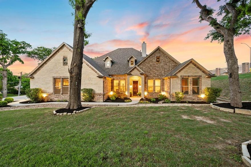 Tucked inside the prestigious guard-gated community of Riverbend Estates, this exceptional home sits on a rare 2.658-acre greenbelt lot with no near neighbors and a large open space maintained by the city, offering the feel of even more acreage without the maintenance. Surrounded by tall, mature trees and a peaceful setting, this property blends privacy, luxury, and thoughtful design while offering a rare opportunity to enjoy acreage within city limits. Inside, rich hardwood floors, soaring ceilings, and an open layout create an inviting atmosphere. The expansive living room features a stunning stone fireplace and flows seamlessly into the kitchen, where recent renovations have transformed the space into a true showpiece. Taj Mahal quartzite countertops, upgraded backsplash, recently replaced tile flooring, double ovens, gas cooktop, oversized island, and wraparound countertop with seating create a sophisticated eat-in kitchen ideal for gathering. A wine cooler, sonic ice maker, and handmade cabinetry further elevate the space. The spacious primary suite has been beautifully updated with Taj Mahal quartzite, a remodeled tub and shower, and upgraded tile flooring, creating a relaxing retreat. This home offers five bedrooms, each with ensuite bathrooms, along with multiple living areas including a massive upstairs game room with built-in speakers. A large mudroom, oversized laundry room with space for a refrigerator, extensive storage, and a rare four-car garage add everyday convenience. Step outside to enjoy the covered patio with an outdoor fireplace and grill, overlooking the large backyard complete with an in-ground heated pool and spa combo. Located minutes from dining, shopping, and major highways including 820, 121, 183, and I-30. The property may be eligible for Birdville ISD via application or transfer; however, this is a third-party process. Neither the sellers, Bray Real Estate Group, nor listing agents guarantee approval by the school district.