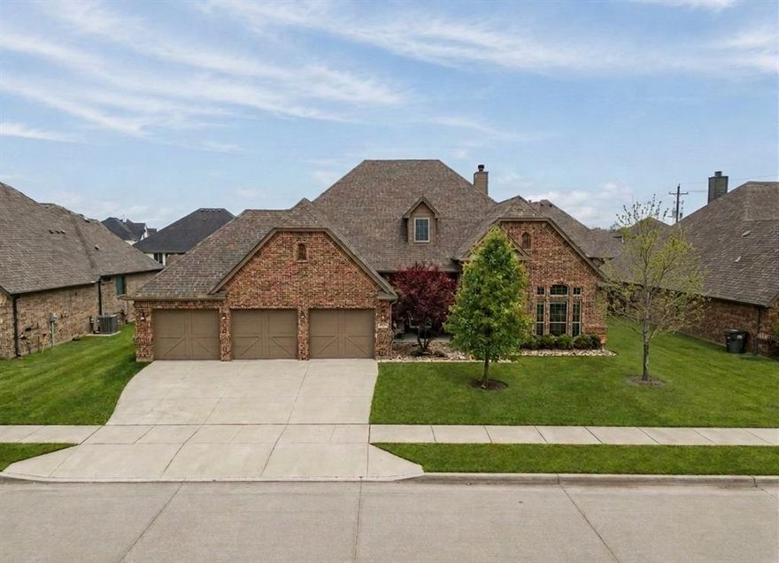 Assumable 3.25% loan. Beautiful custom home on almost a quarter of an acre with beautiful front porch. Exceptional upgrades throughout. Three car garage with additional storage and newly refinished hand scraped hardwood floors that bring warmth and character to the main living spaces.

The chef’s kitchen is designed for both everyday living and entertaining, quartz countertops, a large center island, breakfast bar, and an abundance of cabinetry. The kitchen is already equipped with a propane line, making it easy to install a gas range if desired. The open layout flows seamlessly into the living room, where natural light fills the space and custom built in shelving and cabinetry frame the brick wood burning fireplace.

The home offers four spacious bedrooms and three full bathrooms, including a well designed Jack and Jill bath connecting two secondary bedrooms. The primary suite is a true retreat with a tiered tray ceiling, a spacious and luxurious primary bath, and an impressive walk in closet with extensive shelving and hanging space.

The formal dining room is currently styled as a sitting lounge but easily accommodates a large dining table for gatherings and entertaining.

One of the most charming features of the home is the expansive front porch. This shaded space with a ceiling fan overlooks the beautiful Japanese maple and front yard and offers the perfect place to relax. Located on the final street in the neighborhood, the setting feels peaceful with neighbors often out enjoying bike rides and evening walks.

The covered back patio includes a mounted TV and overlooks a generously sized backyard with plenty of space to create your ideal outdoor living area.