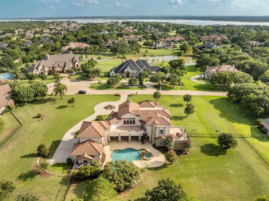 Unforgettable refinement meets timeless beauty in this custom, Tuscan work of art set on over 2 meticulously landscaped acres in the heart of Flower Mound’s prestigious gated community, The Landing at Northshore. A true architectural masterpiece, this breathtaking European estate is a symphony of elegance, craftsmanship, & refined luxury. As if stepping into a story where memories are waiting to be made, picture cozy evenings by the fire, summer pool parties savoring the sunset, & quiet mornings on the balcony overlooking the treed backdrop- life here is nothing short of extraordinary. A spacious covered patio greets you as you enter through the grand iron-accented doors, every detail whispers luxury including the hand-scraped hardwood floors, vaulted ceilings, 3 fireplaces, multiple covered patios & dramatic ironwork accents. Meals are effortlessly elevated in the kitchen with VIKING appliances, 6-burner range with integrated griddle, granite counters, warming drawer, double ovens, expansive island & soft close drawers. A true cinematic escape to the private movie theater featuring a 158-inch acoustically transparent screen, Klipsch surround sound, custom wood entry, two-tiered seating, a half bath & wet bar for elevated movie nights. The home is wired with a whole-house speaker system & boasts custom lighting scenes. Resort-inspired backyard retreat where an expansive covered patio with cool decking overlooks a stunning pool & spa, complete with waterfall, grotto, in-pool tanning platform, & diving-depth section that transforms every summer day into a vacation. Elegant exterior spiral staircase connects the upper balcony to the pool area. Immaculate, oversized 3-car garage makes a statement, featuring gorgeous epoxy flooring, extra-wide doors (two 9-ft, one 10-ft) & walk-in storage closet with built-in shelving- an automotive enthusiast’s dream. 3 beds down & 3 beds up with an expansive game room & second kitchen complete with wine fridge, ice maker, & serving bar