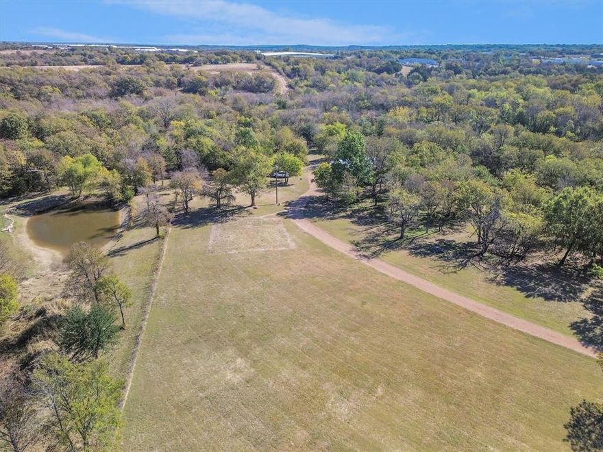 Spectacular 15-acre boutique property convenient to charming downtown Denison shopping & restaurants and minutes from Lake Texoma. Wildlife Management Tax Exempt and within Denison city limits—this rare find offers privacy, natural beauty, and modern convenience near HWY 75 and the upcoming Preston Harbor Development. The land features mature hardwoods, gentle elevation changes, two spring-fed creeks with a small waterfall, scenic trails, and a vintage 40-ft greenhouse. Ideal for recreation, building your dream home, or continuing its wildlife management plan. Winding trails meander along the creeks and through the hardwood canopy, ideal for hiking, ATV riding or simply enjoying the wildlife. Deer, bobcat, fox, owl, raptors, songbirds and more makes their home here. About 60 percent of the acreage is covered with mature post oak, live oak, Shumard oak, Chinquapin oak, ash and an impressive collection of pecan trees. Texas A&M soil tests confirm deep, loamy, slightly acidic soil with the perfect texture & mineral balance for orchards, vineyards or gardens. A professionally built, foam-insulated 40x50 metal building includes a 15x40 finished living area with heat & air, full bath, washer & dryer, microwave, fridge and freezer—perfect as a guest cottage, weekend retreat, or temporary residence while building. The shop portion includes three oversized roll-up doors, heavy-duty loft with a Swedish-style sauna, 200-amp service, 220V outlets, RV hookups, chip-seal driveway, and fenced dog run. City utilities, strong cell service, and Starlink internet already in place. Minutes to Denison HS, McDaniel MS, shopping, and HWY 75 access. Not in a flood zone.