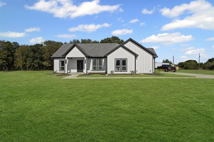 Welcome to your dream home! This stunning modern farmhouse, built in 2022, is nestled on a coveted corner lot in highly sought-after Granbury, with no HOA. The home features eye-catching board and batten wood siding, enhanced by stylish down and up lighting, along with modern outdoor lanterns featuring detailed glass, exuding exceptional curb appeal. Enjoy the privacy and tranquility of 1.091 acres, complete with mature trees in the backyard—perfect for outdoor gatherings and family activities. Step inside to discover an airy open layout adorned with wood grain luxury vinyl plank flooring throughout the main areas, creating a seamless flow. The heart of the home features a gourmet kitchen with a large island, sleek stainless steel and black GE appliances, and illuminated upper cabinets. Plus, a massive 5x7 ft walk-in pantry offers ample shelving and storage for all your culinary needs. Colonial baseboards and windows throughout allow for abundant natural light, enhancing the warm and inviting atmosphere of the home. Retreat to the primary bedroom, boasting an ensuite bathroom complete with a spa-like waterfall shower feature, a stunning chandelier, and soaring 13 ft vaulted ceilings. Relax on the covered back patio overlooking your serene yard, ideal for enjoying peaceful mornings or entertaining guests. This exquisite modern farmhouse in Granbury offers the perfect blend of modern elegance and country charm!