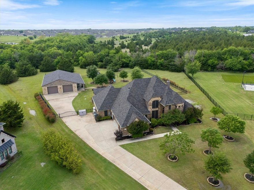 Welcome to this stunning 5-bedroom, 3.5-bath home nestled on two private, tree-lined acres. From the moment you arrive through the gated entrance, the craftsmanship is evident. The heart of the home is a dramatic floor-to-ceiling stone fireplace, anchoring an open-concept layout that flows seamlessly between the living area, dining room, and kitchen. The backyard serves as a true private resort, designed for ultimate relaxation and entertaining. A covered patio leads to a custom-built pool and spa, accented by flagstone coping and a soothing rock waterfall, all powered by Pentair heating and automation for year-round enjoyment. Complementing the pool is a second covered outdoor living space featuring a built-in island with a stainless steel gas grill, granite countertops, and a drink refrigerator all set against a backdrop of mature live oak trees and professional landscaping. The standout feature of this property is the massive 40'x60' fully bricked shop, designed to match the main home. More than just a workspace, this building is a fully finished extension of the home, boasting epoxy floors, a batting cage, and boat storage. Adjacent spaces include a finished, climate-controlled fishing hobby room and a private bar room with Italian tile and custom cabinetry, and its own half bath. A full-length 10'x60' covered patio with LED lighting and ceiling fans runs the entire exterior, providing even more space for work or play. The property is rounded out by exceptional infrastructure, including a new 30-year composite shingle roof installed in 2024 on all buildings, a Kohler whole-home generator, and dual Trane HVAC systems. The grounds feature a 4' wrought iron fenced backyard, full irrigation, and a charming air-conditioned playhouse with a loft. This one-of-a-kind retreat offers the privacy of acreage with the amenities of a luxury resort a rare opportunity that must be seen in person.