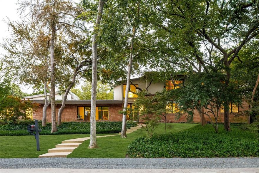 This modernist showplace is located in a private, picturesque setting in North Dallas, with wooded lot and country lane access. The home was expanded in 2013-2014 to include a connoisseur's wine cellar, a delightful parlor and a spectacular infinity pool bounded by beautiful entertaining areas and outdoor kitchen. The master is luxurious with fireplace and inviting balcony and there is a sumptuous master bath with impressive custom closet. Three additional bedrooms enjoy views of the breathtaking grounds and easy access to a large workout room. This lovely home is an elegant retreat in the heart of the city.