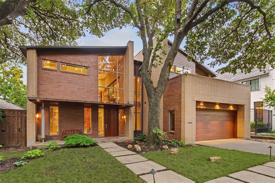 Architectural masterpiece by Mark Domiteaux, inspired by Frank Lloyd Wright’s Meyer May house, this organic modern residence is a symphony of natural materials & thoughtful engineering. Artfully set into the terrain to cascade from front to back, utilizing a timeless palette of Douglas fir, slate, copper, and Norman size brick to emphasize its striking horizontal profile. The experience begins at the oversized front door, where a soaring foyer offers immediate views through the living area to a lush garden anchored by a decades old live oak tree. The interior aesthetics are defined by warm Douglas fir columns, granite surfaces accented with copper backsplashes, and a majestic Arkansas Gold stone fireplace that carries its natural coloration seamlessly from the living room to the adjacent outdoor patios. Extra deep hickory pecan steps with slate risers lead to the upper level, where a library area juts over the foyer to create a cozy bird’s nest retreat with access to private decks nestled within the tree canopy. Beyond its aesthetic brilliance, the home is designed with meticulous attention to functional luxury and longevity. Featuring two primary suites, with the lower suite offering independent heating, hot water, and laundry hookups, making it an ideal solution for guests or multi generational living. For the motor enthusiast, the four car garage serves as a hobbyist's sanctuary, equipped with industrial cooling fans, a transition mudroom, & custom flooring that pays homage to KTM motorcycles. Every detail was chosen for ease of use and durability, including granite and Corian sills designed to withstand sun exposure and stainless steel lateral beams over the patio for minimal maintenance. Abundant built in storage is found throughout, including custom cabinetry in the primary suite & butler’s pantry. This residence is a rare synthesis of high design pedigree & modern utility, complete with 220V electricity for a hot tub installation on the southwest stone patio.