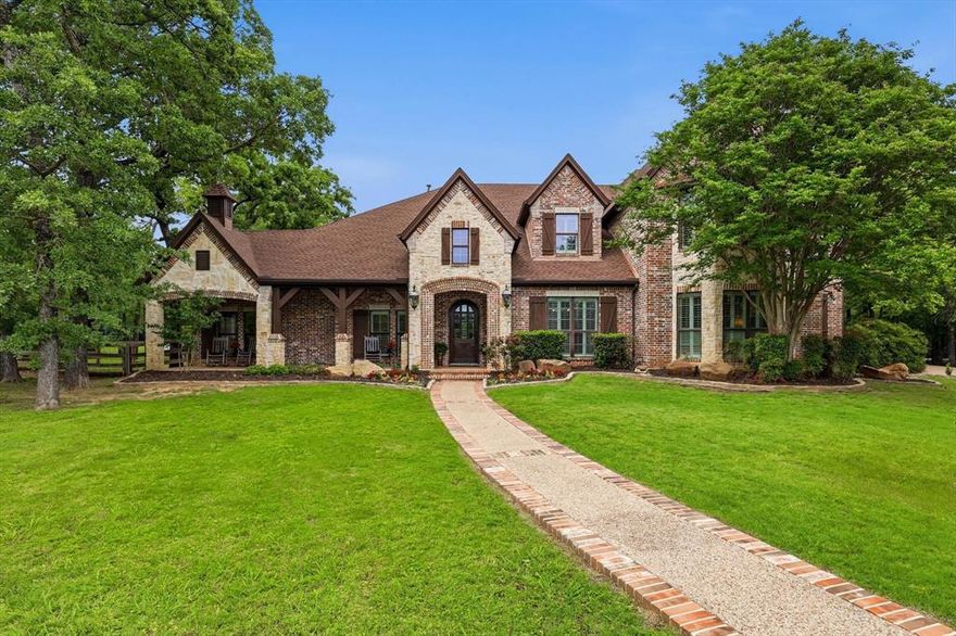 Tucked away at the end of a winding drive, past a peaceful pond that sets the tone the moment you arrive, this one feels like a hidden retreat you didn’t know you were searching for. With 9+ beautifully wooded acres, the setting is pure North Texas charm—quiet, private, and alive with wildlife, towering trees, and trails just waiting to be explored. Completely remodeled and significantly expanded in 2006. 
The home itself wraps you in warmth from the start, beginning with a sprawling front porch made for slow mornings, evening conversations, and everything in between. Inside, natural light pours through dramatic floor-to-ceiling windows, highlighting rich hardwood flooring, stunning fireplaces, and custom built-ins that bring both character and function to every space.
With 7 bedrooms—including 2 conveniently located downstairs—there’s room for everyone to spread out comfortably. Upstairs, the oversized bedrooms feel like their own retreats, with charming lofts and private balconies adding a touch of personality and escape. Four generous living areas create endless flexibility, whether you’re hosting a crowd or carving out quiet corners to unwind. Upstairs game room, media room and more.
The private office is a standout feature all its own—complete with a fireplace, seating area, and abundant built-in storage—making working from home feel anything but routine.
Step outside and the lifestyle really comes to life. Spend afternoons by the beautiful oversized pool and hot tub, challenge friends to a game on your private pickleball court, or cast a line in your own fishing pond. There’s room to roam, space to breathe, and endless opportunities to entertain or simply enjoy the stillness.
A storage building adds practicality. Sought after Argyle and Liberty Christian schools. 
This is luxury living—comfortable, inviting and designed to be lived in and loved. A place where every path leads to something special, and every day feels just a little more like a getaway.