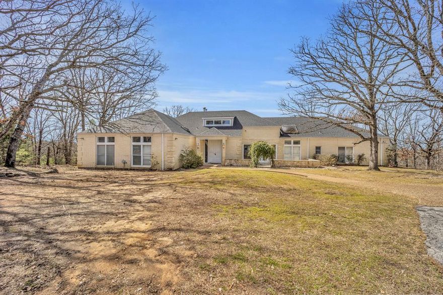 Secluded Architectural Gem on Nearly 12 Acres in Lindale!
Discover a one-of-a-kind architectural masterpiece nestled atop a hill on nearly 12 gated and fenced acres in Lindale. Designed by an architect, this stunning 3,519 sq. ft. home offers breathtaking views from its expansive deck, surrounded by serene, mature trees for ultimate privacy. This unique property features three bedrooms, two and a half bathrooms, dedicated office with fireplace and tons of storage. This home provides an inviting floor plan with character and warmth throughout. The formal dining room and breakfast area boast a cozy fireplace, while the living room and master bedroom each have their own fireplaces, complete with imported mantles that add timeless charm. Gorgeous stained-glass accents throughout enhance the home's distinctive beauty. Additional highlights include an oversized two-car garage, a separate storage building, and endless potential for customization. Built in 1982, this home is a rare find, offering a blend of architectural elegance and natural beauty. Don't miss this opportunity to own a truly unique property in the heart of East Texas! Schedule your private tour today!