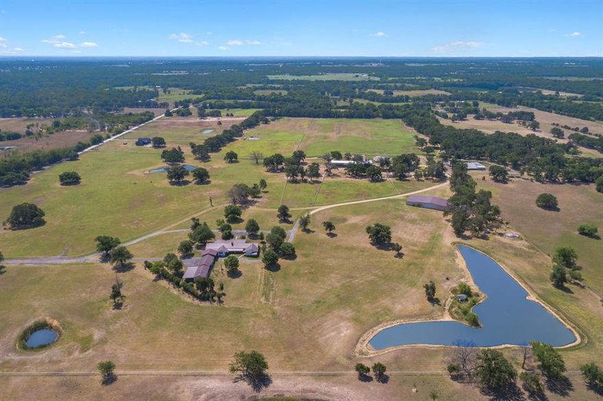 Exceptional 145-Acre Ranch – Just 1 Hour from Dallas! This stunning property features a spacious 3,316 SF, 3-bed, 3-bath home designed for comfort and entertaining. The open-concept layout boasts a large kitchen with custom countertops, stainless appliances, double ovens, an island cooktop, and seamless flow into the oversized living area with a WBFP as the focal point. The expansive primary suite includes a luxurious bath and a massive walk-in closet. Two large guest rooms, a generous utility room, a spacious office, and a 4-car carport provide ample space. Designed as a premier horse ranch, it also supports cattle operations with multiple barns, including a 4,800 SF barn for dry storage, hay storage, equipment, stables, and an outdoor arena. Manicured Bermuda pastures with mature oaks, pipe fencing throughout, and a picturesque setting make this a true Texas gem.