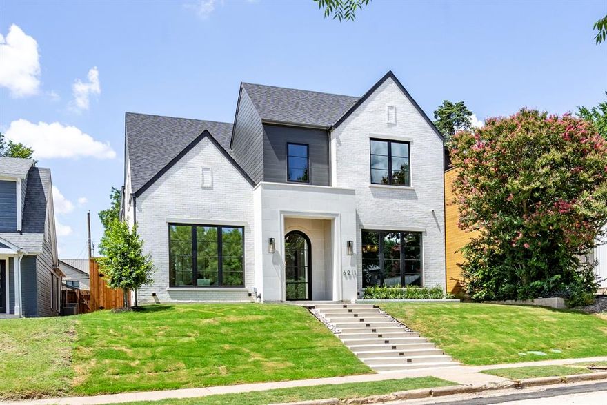 One of Lakewood Heights’ most impressive new builds combines expansive square footage with a premier location near Tietze Park and coveted Mockingbird Elementary. The interiors showcase 11-foot ceilings throughout the main level and an 18-foot vaulted dining room accented by white oak beams and Level 4 smooth-finish walls, setting a dramatic yet refined tone. In the living room, a fluted quartzite fireplace provides a striking centerpiece, while the study is elevated with a custom slat built-in and coffered ceilings. The kitchen blends rift-sawn white oak cabinetry with Mont Blanc quartzite countertops, complemented by a Bertazzoni range, Sub-Zero refrigeration, and Brizo plumbing fixtures. A main-level guest suite with its own bath offers convenience and privacy for visitors. Upstairs, lifestyle amenities abound: a vaulted game room, a dedicated flex room designed as a gym, two secondary bedrooms with en-suite baths, and a luxurious primary suite. The primary retreat features a vaulted ceiling, spa-inspired bath with a freestanding tub enclosed in glass alongside dual shower heads, fluted cabinetry with marble counters, and an oversized walk-in closet with built-in dresser connecting directly to the utility room. Outdoor living is equally thoughtful, with a covered patio featuring a fireplace, built-in grill, and beverage fridge overlooking a pool-ready yard. Infrastructure for future upgrades is already in place, including utilities, oversized breaker capacity for pool equipment, and an EV charger. Andersen 100 windows maximize natural light, while upgraded foundation and framing engineering provide superior build quality. Designer-curated finishes, integrated AV, and a full mesh network complete this move-in-ready home.