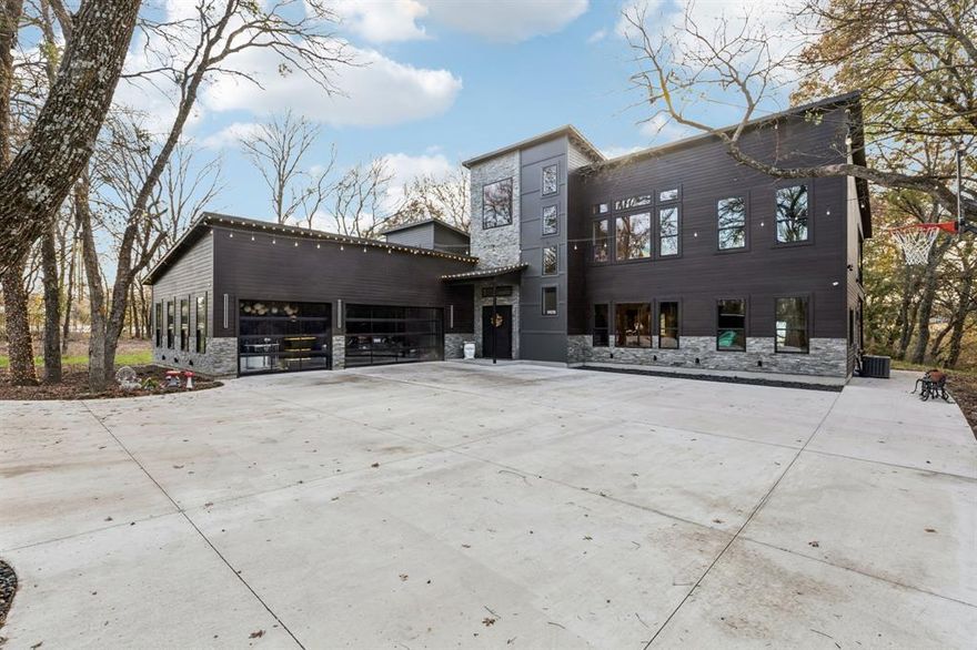 Welcome to an unparalleled masterpiece where modern luxury meets serene sophistication on 2.47 acres backing a private creek. This custom-designed smart home redefines elegance with soaring ceilings, Woodland Reserve Creekside Sawn White Oak wire-brushed hardwood floors, and quartz countertops throughout. The chef’s kitchen boasts Zline appliances, including a 48” propane stovetop with double oven, 30” wall oven and microwave, double dishwasher, and under-cabinet beverage fridge, complemented by waterfall quartz countertops and matching backsplash. Two 32” KRAUS Bellucci granite composite sinks enhance functionality, while a walk-in pantry with a sink adds convenience. The main living area features a gas fireplace with built-in storage, a floor plug for flexible layouts, and a glass-enclosed wine cellar. Retreat to the master suite with a light-up ceiling, electric fireplace, and spa-like bathroom offering an Alpha bidet, dual shower with rain head, skylight, and stand-alone garden tub. Smart home technology, including Z-Wave switches, 5 alarm cameras, and 3 touchscreen control centers, allows seamless control of lights and thermostat. The media room, hidden behind a bookshelf door, boasts a 132” projector screen, 8K Ultra-HD receiver, and MartinLogan speakers, plus a beverage fridge and private balcony. Outside, a wood-burning fireplace warms the back patio, joined by an outdoor kitchen with a Traeger Timberland XL and kegerator. Titanium black quartzite stone, cedar siding, and black modern pebble landscaping frame the shingle-roofed estate, with a 3-car extended garage and custom black-trim windows. A 1,260 sq ft metal building with an 840 sq ft porch, pre-plumbed for a bathroom, offers endless possibilities. Experience luxury living with unmatched privacy and creek views. Schedule your private tour today!