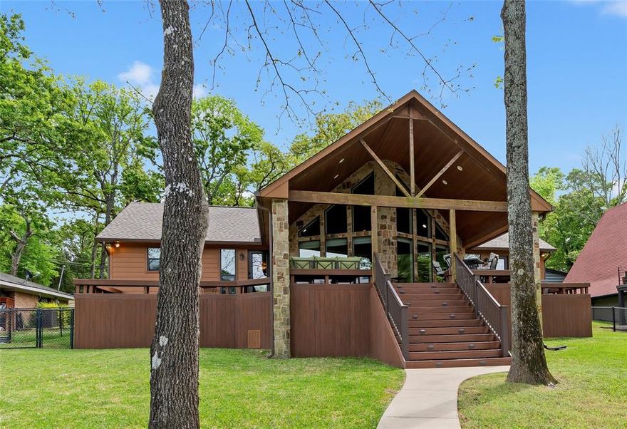 Timeless lakehouse-style home with a versatile guest house, located in a gated community offering a boat launch, park, and clubhouse. The main home features 1,715 sq ft with 4 bedrooms and 2 baths, complemented by a 1,152 sq ft guest house with 2 additional full baths and flexible living and sleeping spaces—ideal for hosting family and friends. Inside, dramatic walls of windows rise to a vaulted pine ceiling, filling the home with natural light. Recent updates include durable luxury vinyl plank flooring and a built-in bar with wine refrigerator. The stone wood-burning fireplace and kitchen with granite countertops add warmth and character, creating a comfortable, inviting atmosphere. The two-story guest house expands your options, with a spacious downstairs room featuring a full bath, wet bar, and wood-look tile flooring—perfect as a game room, bunk space, or additional living area or combination of all 3. Upstairs offers another full bath, living or sleeping space, plus two additional bedrooms. Outdoors, a generous covered deck with wood ceiling overlooks a lovely, treed yard with peaceful cove views. A detached 280 sq ft shed garage provides ample storage for water toys and lawn equipment, while the circle drive allows for plenty of parking. The fully fenced backyard is ideal for pets and kids. A boathouse and lake fed sprinkler system complete the package—everything you need for the perfect lake getaway. The cedar-look Hardie Board siding delivers classic lakehouse charm with low-maintenance durability. New roof and gutters installed in 2025. Furnishings are included for a turnkey opportunity. Conveniently located just around the corner from Pinnacle Golf Club, where social and golf memberships are available, along with a pay-to-play option. Starlink internet available.