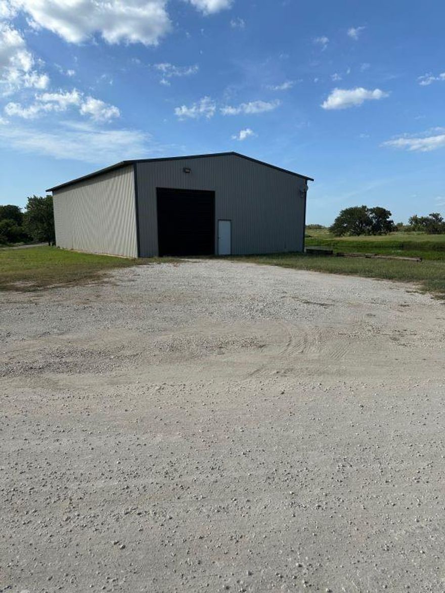 This 4 acre improved lot is located at the corner of W Washington Street and Gibbons Road  (asphalt pavement).  The property  includes a large pond with dock and a 40x60x16 metal warehouse shop  with concrete floor and a 400 sq ft insulated and air conditioned office.  At present, there is no water supply or septic system on the property. However, the building is plumbed  and wired for restroom, sinks, shower, and washing machine dryer. 
A hot water heater and water pressure tank have been installed.   A 200 Amp 40 circuit electrical panel serves  115-230 volt power throughout the building up to and including 50 Amp outlets.  Warehouse lighting is provided by high intensity LED ceiling fixtures. 14 foot remote controlled powered overhead  doors are installed on each end of the building which allows drive through of large RV trailers, boats and motor homes. Entry and exit to and from the building are from either W Washington Street or Gibbons Road.