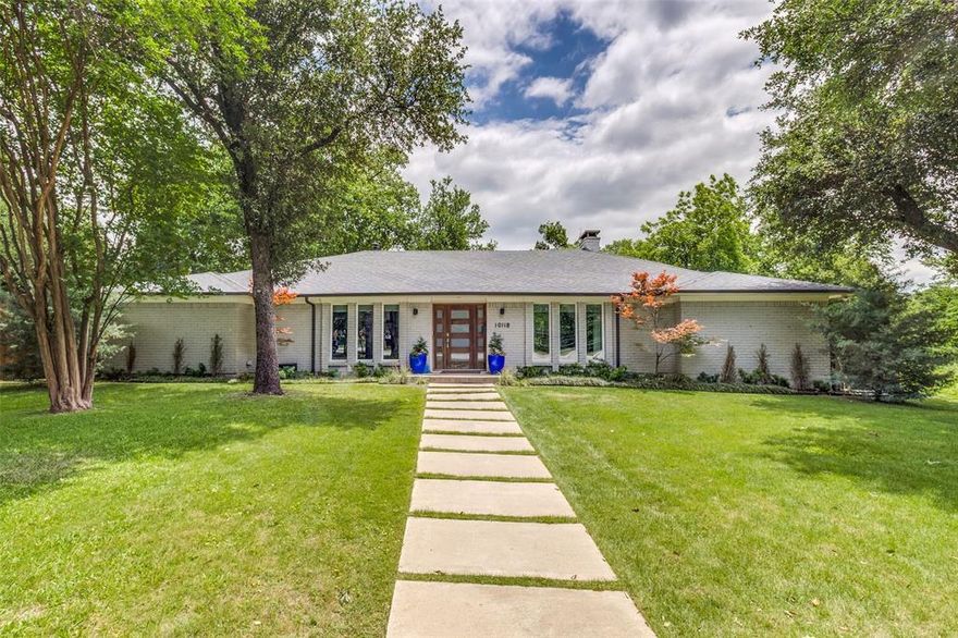 Welcome to this renovated transitional ranch tucked away on a quiet cul-de-sac in one of Dallas’ most desirable pockets. Situated on an incredibly rare .424-acre lot beside neighborhood greenspace, this home offers exceptional privacy while remaining minutes from Love Field Airport, Preston Royal Village, & popular Dallas dining & shopping. From the moment you arrive, the stunning curb appeal, mature landscaping, & painted brick exterior set the tone for the designer touches found throughout the home. Inside, the light-filled floorplan was designed for both entertaining and everyday living, featuring vaulted ceilings, high-end LVP flooring, & a striking floor-to-ceiling brick fireplace. The open concept living & dining spaces connect seamlessly to the fully renovated kitchen with quartz countertops, waterfall island, custom cabinetry, SS appliances, & designer finishes. A dedicated office with closet offers flexibility as a fourth bedroom or playroom. The spacious primary suite features a huge walk-in closet & spa-inspired ensuite bath with dual vanities, oversized shower, & soaking tub. One secondary bedroom is privately positioned on its own side of the home with separate exterior access & adjacent full bath—ideal for guests, multigenerational living, or a quiet retreat. Rarely found in this area, the expansive & private backyard features an oversized stamped concrete patio, huge grassy yard, mature trees, & motorized gate—creating the perfect setting for entertaining or everyday living. Additional upgrades include new windows, roof replacement in 2020, foundation work with transferable lifetime warranty, cast iron plumbing replacement, & updated electrical. The neighborhood is known for its strong sense of community, including annual Halloween festivities & Christmas light walks—all without HOA restrictions. Offering a rare combination of lot size, privacy, flexible layout, one-story living, & central Dallas convenience, this home is truly a rare find.