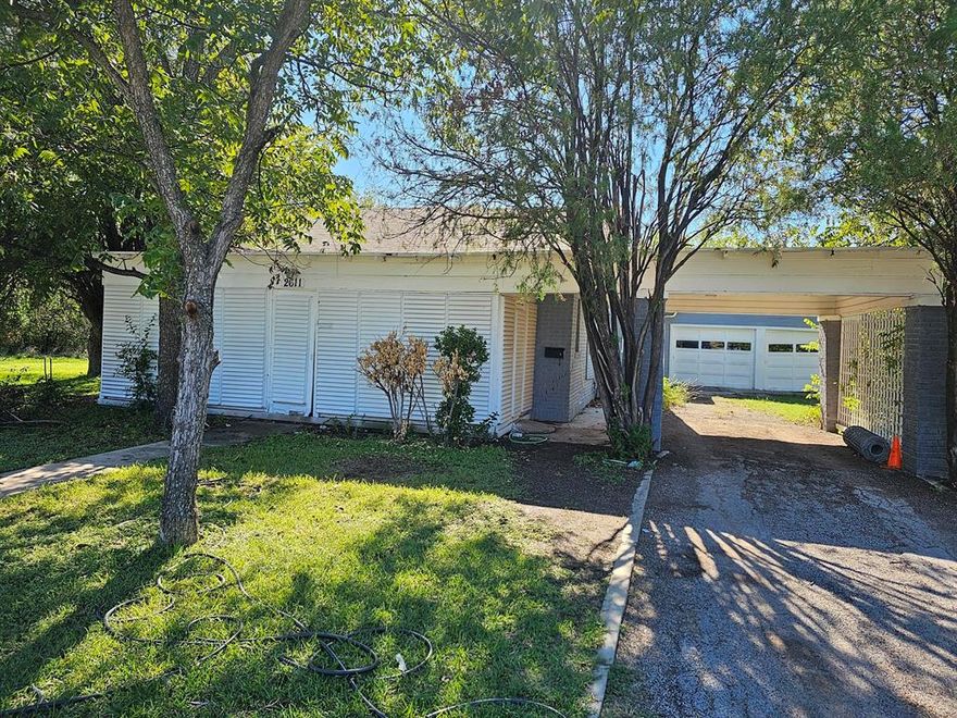 HUGE PRICE REDUCTION!!!!!  SPACIOUS 3 BEDROOM, 2.5 BATH HOME WITHIN WALKING DISTANCE TO EAST ELEMENTARY!  House sits on 2 lots totaling 1.03 acres.  Fenced backyard is huge with lots of room for the kids and animals!  There is plenty of room to build a shop etc. The 2nd lot is covered in trees and is directly behind backyard with gate access.  House has 2 living areas; the den in back has a woodburning fireplace. The middle bedroom is currently being used as additional closet space.  There is ample parking with a carport and double garage.  Updates done in 2022:  new AC unit, replaced plumbing lines, new paint on exterior and also interior, new dishwasher, new wood laminate flooring. House is sold as-is.  Conventional loan or cash buyers only!  This home has lots of potential for the right buyer!!