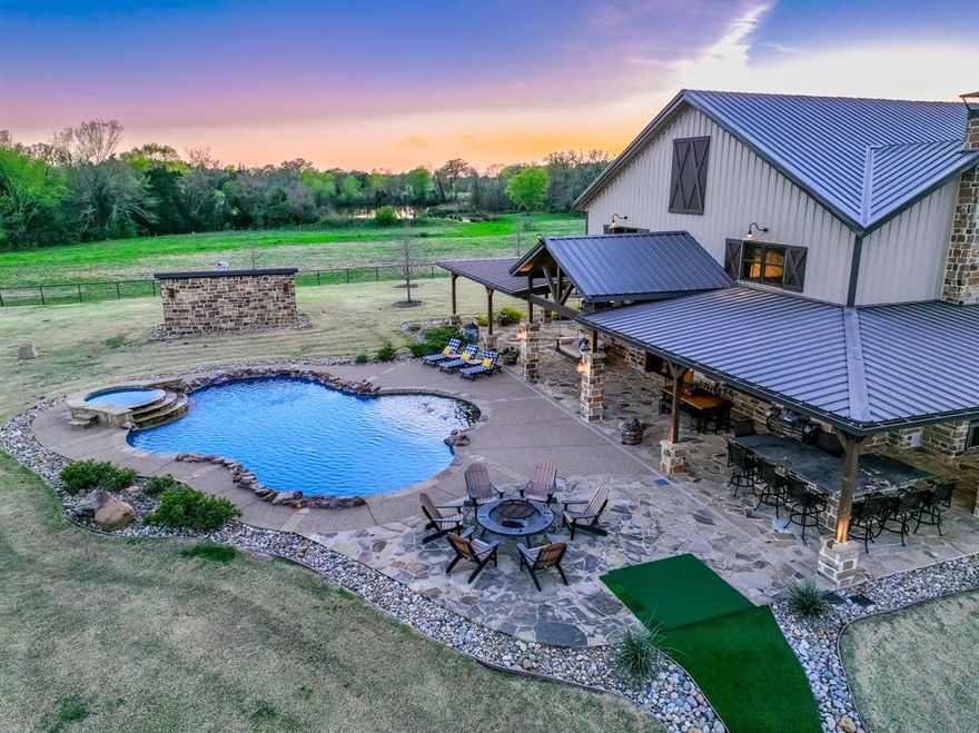 Discover your private country retreat in Edgewood, TX – a luxurious 4,954 sq. ft. custom Bardominium nestled on a stunning 11+ acre estate. Just 10 minutes from Canton & an hour from Dallas, this Van Zandt County treasure offers the perfect blend of rural tranquility & urban accessibility. Step inside to a world of rustic elegance, where white pine ceilings with Douglas Fir beams, rich hardwoods, textured walls, & knotty-alder cabinetry exude refined, country charm! The heart of this home is the kitchen, featuring stainless steel appliances, a Thermador 6-burner range with griddle, steamer, & pot filler, plus quartzite counters with raw edges, a coffee bar, walk-in pantry, and oversized island. A ventless fireplace, custom lights, & toe-kick vac system elevate the space! The spacious living area features a floor-to-ceiling stone fireplace with custom pecan mantle, complemented by plantation shutters & built-in cabinets. The owner's suite boasts custom-barnwood ceilings & a spa-like en-suite with claw-foot tub nestled in a stone alcove, walk-in shower, & his-and-her closets connected to the laundry. Another bedroom, full bath, & safe room complete this level. Upstairs, 3 spacious bedrooms offer ample room for family & guests, 2 featuring en-suites! Then, a massive 2,000 sq. ft. industrial-sized shop with FIVE 9'x12' automatic doors, built-in Craftsman's, central vac system, and lift up to a 2,500 sq. ft. loft offers endless possibilities!! And finally, step outside to discover the BREATHTAKING scenery & entertainment that awaits!  A large, fully stocked pond filled with bass and catfish features a custom dock & water fountain with color-changing lights. Back at the homestead, a wrap-around stone patio boasts an outdoor kitchen, bar, & speaker system. Enjoy your own putting green, a heated pool and spa, & plenty of room for a firepit, all surrounded by lush landscaping. This property isn't just a home – it's your personal retreat for both relaxation and adventure!