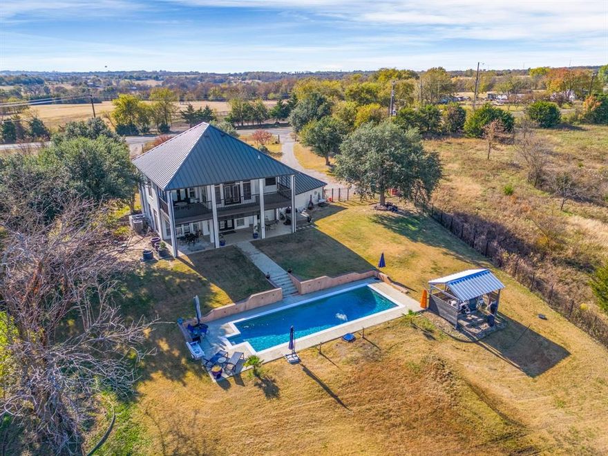 LOCATION, ACREAGE, UPDATES, and a POOL! UPDATED HOME on a 1.21-ACRE beautiful, FULLY FENCED lot 1 MILE from HWY 75 in desirable Howe with a POOL! Looking to escape the congestion of suburbs under constant development? This unique property is not your cookie cutter home, but instead an entertainer's dream displaying extensive recent upgrades inside and out. Enjoy resort-style living with the sparkling saltwater pool (new pump, filter, salt cell, and equipment roof and housing in 2023) complete with a gas heater for year-round enjoyment. The exterior is an absolute showstopper highlighted by a massive 1,288 sq ft of covered patio space across the upper and lower decks offering incredibly stunning sunset views from both the upper and lower balcony and patio. Entertain rain or shine on the lower covered patio effortlessly controlled by five new motorized patio screens (2025). The property features a new roof (2023), and is enclosed by a full-property 6-foot iron fence with two electric entry gates for privacy and security. Interior updates boast a fully remodeled kitchen and primary bath, a new whole-house water filtration system, new fixtures and lighting throughout, updated real wood stairs, and newly stained concrete floors downstairs for easy maintenance; the third bedroom even has heated flooring! The property also includes an outdoor wood storage shed with a metal roof (built 2022) and a new irrigation system. For the electric vehicle owner, EV wiring is already in place! The hot tub and a John Deere zero-turn mower can convey with the property with an acceptable offer. Don't miss this opportunity to own a truly unique, turn-key estate that is the perfect blend of peaceful country living with the convenience of easy highway access, and say hello to clear, star-filled nights!