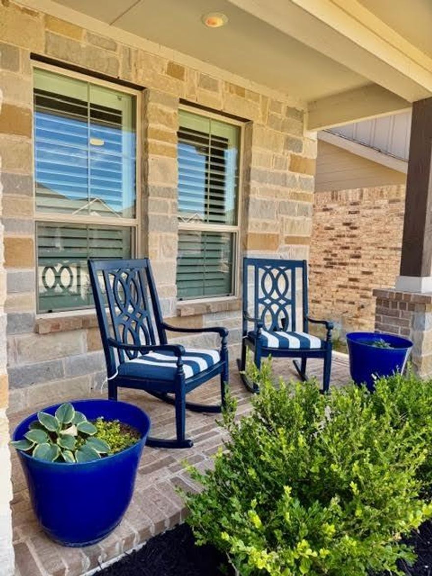 Welcome home to this corner lot next to a greenbelt and beautifully designed 4 bedroom, 2 bath residence in the sought after Pecan Square community, where charm, luxury, and incredible amenities come together. Relax in rocking chairs on the oversized front porch or unwind under the covered private back patio plumbed for gas, perfect for outdoor entertaining. As you enter the home, you will find porcelain ceramic wood look tile, designer ceiling fans & light fixtures, elegant plantation shutters that open from the top or bottom for added privacy and natural light. The stunning kitchen features gray cabinetry, a stylish herringbone backsplash, under cabinet lighting, farm sink, coffee and wine bar designed for entertaining. The oversized primary suite provides a relaxing escape, while two secondary bedrooms and a full bath offer additional privacy doors, creating an ideal setup for guests or multigenerational living.  Additional highlights include a tankless water heater and an oversized laundry room.  Enjoy the unmatched lifestyle of Pecan Square with resort style amenities including a community pool, amenity center, gathering area, work out center, pickleball and basketball courts, farmers markets, and breathtaking sunsets from the hilltop terrace and Elm Tower chapel. The home furnishings and most items are also for sale. PROFESSIONAL PICTURES COMING SOON.