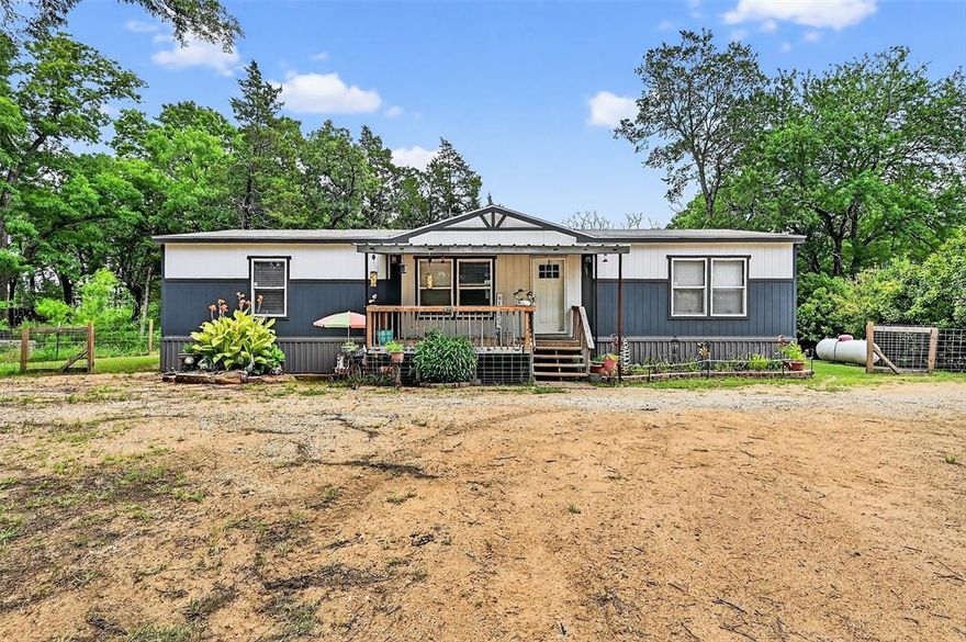 Welcome to peaceful country living with room to grow and improvements already in place. This well-maintained manufactured home sits on a concrete pad that was added just a couple of years ago and remains under warranty through June 2027, offering added peace of mind. The home features a spacious living room and an open-concept floor plan that flows seamlessly into a large kitchen, creating an inviting space ideal for everyday living, cooking, and gathering with family and friends. Step outside onto the back patio and unwind while taking in serene views of a pond, the perfect backdrop for quiet mornings or relaxing evenings. Adjacent to the home, a covered outdoor living area has been thoughtfully designed to accommodate cooking, canning, and entertaining, making it ideal for those embracing a self-sufficient lifestyle. Just off the back porch, an underground container provides additional storage or storm protection, adding both practicality and security. The property is well-equipped for homesteading or hobby farming, featuring a greenhouse for year-round growing, a spacious shop for projects or equipment, a large carport for covered parking, and a dedicated tractor shed. An RV hookup with water and electricity adds even more flexibility for guests or travel convenience. A 24kW generator ensures reliable backup power, while frost-free hydrants provide ease of use year-round. To top it off, a hot tub with a two-year warranty offers the perfect place to relax after a productive day. With infrastructure already in place and 3.5 usable acres to make your own, this property delivers the freedom, functionality, and peaceful setting so many buyers are searching for. Come experience the possibilities and envision creating your own private homestead retreat.