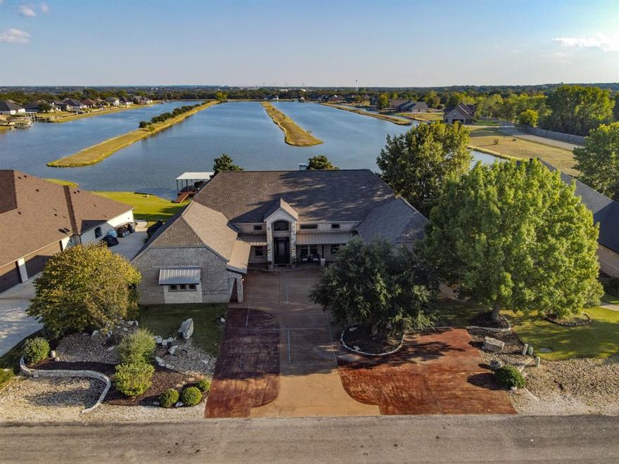 Experience serene lakefront living in this stunning two-story, 3,368-square-foot brick home fronting a private ski lake with close by convenient access to launch your boat into Lake Granbury. Designed to maximize natural light and capture breathtaking water views, the home features expansive windows across the back, creating a bright, airy atmosphere and a seamless connection to the outdoors.

The family room is the heart of the home, offering high ceilings, large picture windows, and an open layout that flows effortlessly into the chef’s kitchen, perfect for entertaining and relaxed lake living.

The primary suite is a true retreat, complete with a cozy fireplace and panoramic lake views. The ensuite bath offers a spa-like experience with a free-standing soaking tub, separate walk-in shower, dual vanities, and his-and-hers walk-in closets. A convenient stackable washer and dryer add functionality to this luxurious space.

With four bedrooms three and one half baths, this home provides plenty of room for family and guests. Thoughtful storage solutions are found throughout, and two attached garages offer ample space for vehicles and lake toys.

Enjoy outdoor living at its best with an exterior shower—perfect after a day on the lake—and a sprinkler system that keeps your lawn lush year-round. Accent lighting showcases the beauty of the home from both the road and the lake, making it a standout day and night.

This exceptional property blends comfort, style, and convenience—ideal for those seeking the perfect lakefront lifestyle.