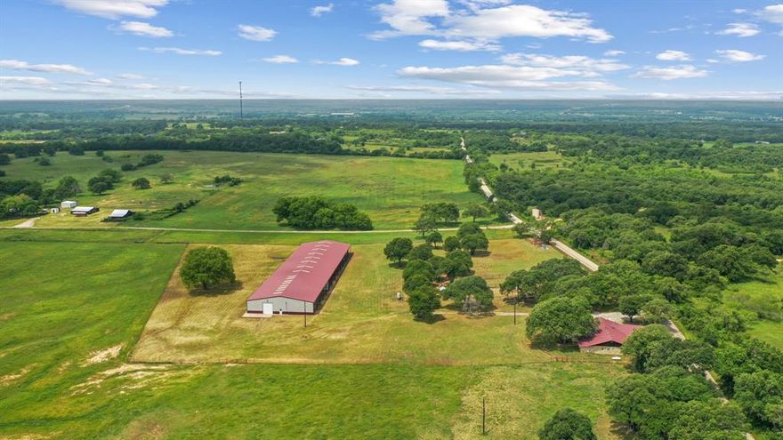 This is a rare find & unique opportunity to own 85 gorgeous acres of coastal fields just 1 hour west of the DFW Metroplex. And, it has a covered arena! Fenced & cross fenced, this property can support cattle or equine operations. Looking for a getaway where you can watch deer and wild turkey as you fish in 1 of the property's 2 ponds, this is the place. Need a place to expand your working ranch, there's space to customize and make this one extra special. The home has good bones w some updates and just needs cosmetic finishes. The stall barn could easily be improved with runs as there are pipe pens off both sides. The shining gem is the 100x265 metal building. Inside, you'll find a 100x50 enclosed shop with electricity, a large sliding door and plenty of space for storage or tinkering. There's also a 30x100 overhang for additional storage. Off the back, there is a 165x80 covered riding arena that could suit many disciplines. Imagine the breakaway calf lane you could have!