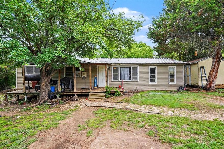 Blocks from Lake Whitney, this charming 3-bedroom, 1-bath home sits on a spacious .409-acre lot with room for horses or goats. The metal roof is approximately 5 years old, and a covered front deck provides a great place to relax and enjoy the peaceful setting. The converted 1-car garage adds a versatile bonus room with two closets—perfect for a 4th bedroom, game room, or office. All bedrooms feature ceiling fans. The eat-in kitchen includes a gas range and dishwasher. Outside, you'll find a large storage shed and a separate workshop with electricity that houses the washer and dryer hookups. Property is serviced by co-op water and electric and includes two septic systems, offering flexibility for future use. Located in Hill County, just minutes from Lake Whitney recreation.