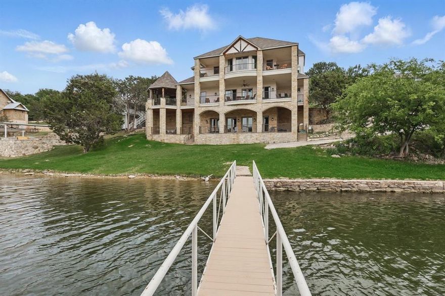 PK FAVORITE! A Spacious Masterpiece! Mediterranean style resort home at Possum Kingdom Lake offers stunning lake views near Bluff Creek Marina. It features three floors with covered balconies and an elevator for easy access. The penthouse primary suite has a private sitting area and coffee kitchenette. The second-floor balcony hosts an outdoor kitchen with abundant observation decks and seating, perfect for entertaining. Inside, is the main living area with lakeview dining options, comfortable seating around fireplace, and gourmet kitchen, and bedrooms. This middle floor also serves as the entry level with an attached garage. The lower lake level is ideal for guests with a pool table, kitchenette, more sleeping areas and access to the lakeside lawn, private beach, and double-decker dock. This location supports swimming, boating, relaxing, and potential short term rental income. Fully furnished and move-in ready. See property video PKFAVORITE DOT COM
