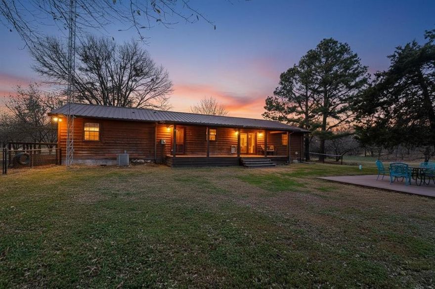 You won’t find prettier land! Incredible opportunity to own your own private paradise at an amazing price—just about 1 hour from Downtown Dallas. Nestled on nearly 5 acres of beautifully treed, fenced land, this charming log cabin retreat offers peace, privacy, and endless possibilities.
The home features a spacious open living area and a light-filled kitchen with serving bar and walls of windows overlooking the serene, natural surroundings. The private primary suite includes a modern bath with dual vanities and two walk-in closets, while three additional bedrooms are thoughtfully separated for added privacy. Step outside to an expansive covered wood deck, perfect for morning coffee, entertaining, or simply enjoying the abundance of wildlife and peaceful views. The property boasts two ponds, including one with a dock ideal for fishing. Additional improvements include two barns, a storage building, and a carport suitable for boat or RV parking—perfect for hobbyists, outdoor lovers, or those seeking a true country lifestyle. This rare opportunity won’t last long—hurry and claim your slice of paradise!