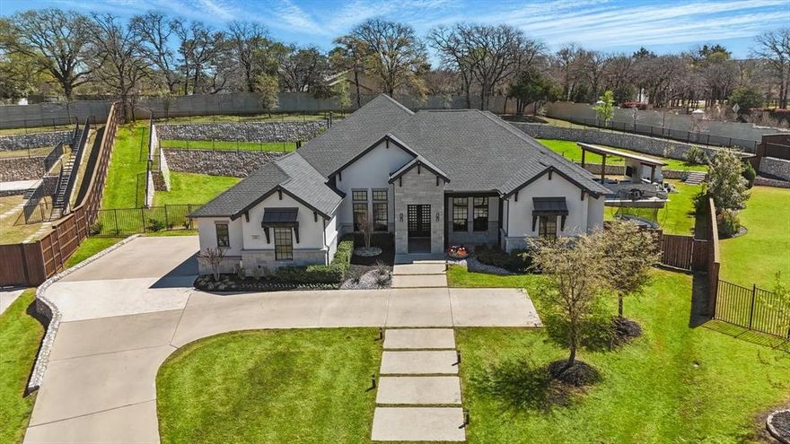 In the heart of exclusive Southlake, this rare single-story estate offers over 4,700 square feet of sophisticated living space on a sprawling nearly 1-acre lot. Step inside to discover a grand open floor plan with soaring cathedral ceilings and designer chandeliers, creating a bright and sophisticated feel throughout. The chef-inspired kitchen is a true highlight with high-end Jenn-Air appliances, double ovens, a 6-burner gas range, quartzite counters, a massive 10-foot island, dry bar and 2 built-in wine coolers. The primary suite is a serene retreat, complete with views of the stunning Claffey pool, electric shades, a grand en-suite bath and 2 custom closets. The secondary bedrooms also have custom-designed closets for added style and functionality. Multiple living areas and home theater offer ample space for relaxation and entertainment. Seamlessly blending indoor and outdoor living, this home has two sets of triple sliding doors, allowing for effortless transitions between the spacious interiors and the breathtaking backyard. Step outside to your private resort—an entertainer’s dream. Enjoy a sparkling ozone pool with waterfall and fountains, a serene gazebo ideal for dining or unwinding, and the added convenience of a pool bath and outdoor shower. Expansive outdoor living areas are perfect for gatherings, while the abundant lawn space provides plenty of room for play and outdoor activities.
Don’t miss your chance to own this unparalleled cul-de-sac property that combines lavish living with exceptional outdoor spaces. Home is also in the award-winning Carroll ISD.