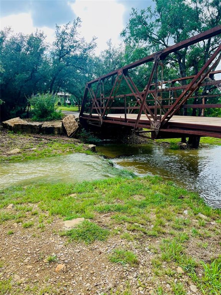 Discover your own Texas retreat with this unique 3-bedroom property on 5 beautiful acres! One bedroom is a charming open loft, while the primary suite is an impressive custom-built wing measuring 16' x 30'—a true private sanctuary.
Enjoy the outdoors from the expansive wraparound porch, where you can take in views of your land featuring a picturesque old iron bridge and a fish-stocked pond perfect for peaceful afternoons. Host gatherings at the patio deck by the pond or under the spacious 30' x 40' pavilion with a cozy fireplace. The distinctive silo pavilion with a 24' circumference adds rustic character and endless entertaining potential.
The property is conveniently located between two county roads for easy access and is not far from water access to the lake—ideal for weekend boating or fishing. It’s also served by SUD water for added peace of mind.
A versatile barn (15' x 20' plus a 30' x 50' area) offers endless possibilities, and above it, you'll find guest quarters efficiency apartment—perfect for visitors, rental income, or multi-generational living. Step onto the upstairs balcony from the guest quarters and enjoy a breathtaking spot for gateway hill-country viewing and star gazing—a true highlight for quiet nights.
With its beautiful setting and versatile spaces, this property could even be a potential venue for special events, retreats, or weddings. The eat-in kitchen, pond-side patio deck, and charming features throughout add to its authentic country appeal.
Bring your vision and creativity to this special slice of Texas paradise a perfect blend of custom comfort, outdoor living, and rustic charm.
Don’t miss out schedule your private tour today and see all the character and opportunity this unique property has to offer!