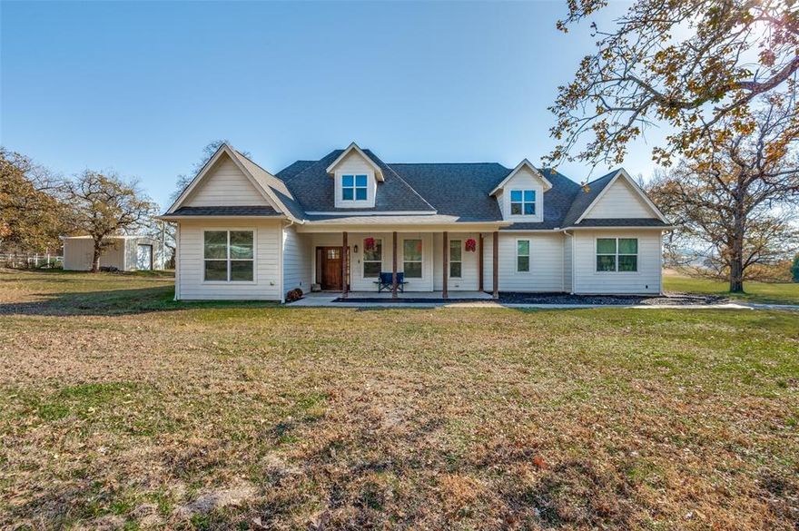 Welcome home to this stunning modern farmhouse, perfectly positioned on a serene 2-acre country paradise. This thoughtfully designed home blends timeless charm with contemporary comfort. From the moment you arrive, the expansive front porch invites you to slow down and stay awhile. Step inside to an impressive open-concept floor plan highlighted by rich hardwood floors, custom built-ins, and modern decorative lighting throughout. The vaulted living room ceilings and massive picture windows flood the space with natural light, while a custom wood-burning fireplace anchors the room with warmth and character. The spacious eat-in kitchen, seamlessly connects to the living area—perfect for everyday living and entertaining alike. Enjoy stainless steel appliances, granite countertops, and a large center island with seating. Retreat to the private primary suite featuring a jetted soaking tub, oversized walk-in shower, separate vanities with quartz countertops, and a generous walk-in closet. Step outside to the covered back porch and take in the peaceful surroundings—mature trees, open skies, and tranquil views of the adjacent pond create a true country escape. Completing the property is a 20x30 metal workshop storage building, ideal for hobbies, tools, or all your recreational toys. This exceptional modern farmhouse offers the perfect blend of comfort, craftsmanship, and countryside living—an opportunity not to be missed.