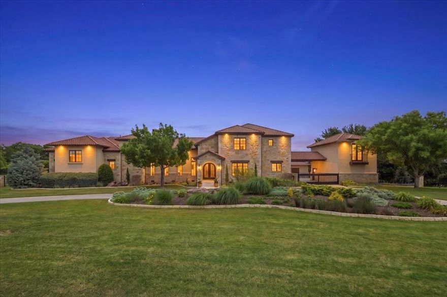Set across more than 7 acres in the exclusive enclave of West Hills Estates in Aledo, this private estate is defined by scale, craftsmanship, and livability rarely replicated. Originally constructed with enduring quality and expanded by renowned builder David Lewis, the residence spans over 6,600 square feet, balancing everyday living with large-scale entertaining.

A custom iron entry door opens to interiors where volume and detail take center stage, with hand-scraped hardwoods throughout. The main living room features soaring 20-foot ceilings, wood beams, and a floor-to-ceiling stone fireplace. The kitchen overlooks the back patio and is appointed with Sub-Zero refrigeration, JennAir ovens, gas cooktops with pot filler, and a spacious eat-in area.

Adjoining spaces include a great room with its own fireplace, stone accents, slate flooring, and wood sliding doors to a second covered patio, along with a fully equipped wet bar with wine fridge, ice maker, dishwasher, and microwave drawer, allowing the home to transition effortlessly from daily living to entertaining.

The primary suite is privately positioned on the main level with patio access, dual closets, a coffee bar, and a spa-inspired bath with soaking tub and dual-head shower. Upstairs, secondary bedrooms are complemented by a Jack-and-Jill bath, along with a secondary primary suite featuring an ensuite bath, walk-in closet, and private balcony access. The main residence offers four bedrooms, three full baths, and two half baths, plus a separate garage apartment with an additional bedroom and full bath.

Outdoors, multiple fireplaces extend the living experience, including a double-sided fireplace on the main patio and another off the great room. A deep chlorine pool, sport court with pergola seating, and an outdoor kitchen with BULL grill and Green Egg create ideal spaces for gathering. A private trail winds through the acreage, enhancing the property’s sense of space, privacy, and one of a kind feel