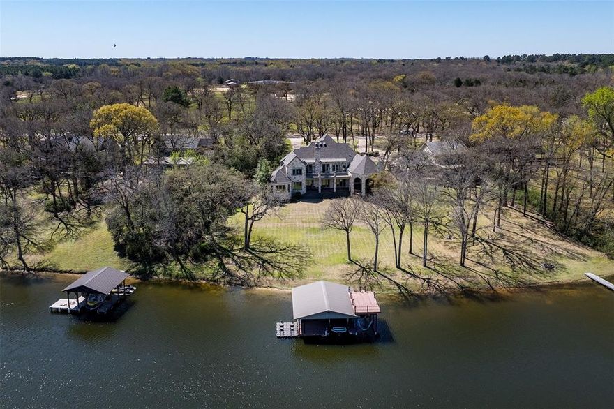 This is WATERFRONT living at its finest. Located on coveted Impala South, an established neighborhood close to town and all its amenities, this impeccably maintained lakefront home offers the perfect blend of luxury, comfort, and privacy. Designed for both relaxation and entertaining, the main level features a spacious primary suite with a separate office within the master wing, a secondary en-suite bedroom, and a gourmet kitchen with an attached bar area, multiple refrigerators, a warming drawer and walk in oversized pantry. Inside, a beautiful stone fireplace adds warmth to the living space, while the outdoor patio features another stone fireplace—perfect for cool evenings by the lake. Upstairs, there’s plenty of space for guests with two additional en-suite bedrooms, a large secondary living area, and a bunk room. The oversized boat dock with a sun deck on top offers great water depth, making it ideal for boating, swimming, and soaking in the views. With a three-car garage, a spacious laundry room, and ample storage, this move-in ready home is a rare opportunity to enjoy the best of lakefront living.