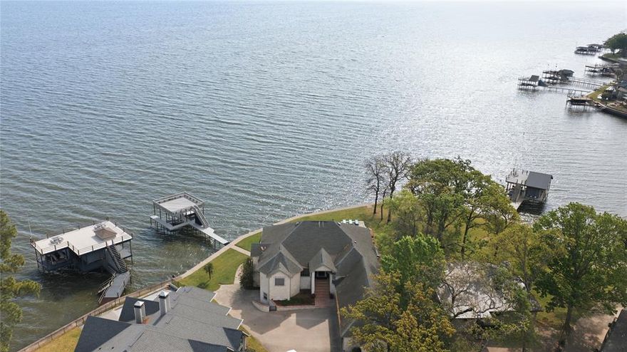 Amazing builders home designed for entertaining family, friends, or large gatherings. The main living area features warm wood ceilings with exposed beams, expansive windows, and glass doors that open to a huge balcony showcasing breathtaking water views. The stunning kitchen is both functional and stylish, offering dual islands, quartz countertops, Sub zero refrigerator, oven, micro wave and convenient warming drawer. The primary suite offers raised ceilings, wall of windows, and a spa inspired bath with dual vanities and an oversized walk in shower. An addition guest bedroom with a full bath is also located on the main level. The downstairs living area is perfect for hosting, complete with a wet bar, large windows, and doors that open to a covered outdoor space featuring an outdoor bar and bathroom. Two guest bedrooms, two baths, and a hidden media room provide great accommodations for guests. Outdoor living is exceptional with a pool, hot tub, and sunning areas. Situated on an open water lot with desirable southeast exposure, mature trees, and incredible lake views.