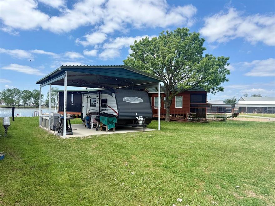 Why pay RV or boat storage when you could own your own slice of the lake? This unique waterfront lot in the gated Pelican Isle community on Richland Chambers Lake offers a smart, turnkey setup that’s ready to enjoy from day one.

Set on a compact footprint with BIG lake lifestyle, this improved property features approximately 5 feet of shoreline with a steel retaining wall—perfect for fishing, launching a kayak, or simply relaxing by the water. A covered concrete pad is already in place, ideal for your RV or outdoor living setup, making this a true “plug-and-play” getaway.Even better, the property includes a 2016 Dutchmen Aspen Trail travel trailer (21.5 ft), already positioned under the cover. Inside, you’ll find a comfortable layout with sleeping space, dinette seating, kitchen with appliances, and a full bathroom—everything you need for weekend escapes or extended stays. Prefer just the lot? The seller is open to negotiating a reduced price without the RV.

Utilities are already installed, so you can pull in, plug in, and start enjoying lake life immediately—no building, no waiting. As part of a gated community, you’ll also enjoy access to a private boat ramp, clubhouse, swimming pool, park, playground, and fishing areas—giving you all the perks of lake living without the maintenance of a larger property. Relax, unwind, and make the lake your backyard. Seller is motivated and will consider all offers.