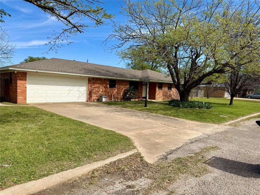 Ready, Set, Go: SET in the perfect location, GO to school or stores by bike or foot, and READY to move in. This all brick homes on three lots has fantastic outdoor living area with generous yard and solid neighborhood in the heart of town. 3 bedrooms and 2 baths with original tile. Ranch style layout including large eat in kitchen. Brick walled fireplace den that practically begs you to snuggle in and relax.  A bonus room off the spacious 2-car garage offers a myriad of possibilities—home office, hobby room, workout space, storage, or anything your lifestyle calls for. Large workshop in backyard for hobbies. All that’s left to do is move in and make it yours!