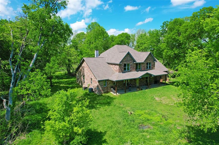 Discover your private escape on this 5.5-acre wooded estate.  This Craftsman-inspired brick traditional greets you with a sprawling front porch and a grand two-story foyer featuring a dramatic staircase. Designed for high-capacity living and entertaining, the heart of the home is a voluminous living room with a floor-to-ceiling stone fireplace and a chef’s kitchen boasting an expansive island and a rare dual-pantry system. The main level offers a private primary retreat with a spa-like ensuite and patio access, plus a secondary guest bedroom. The oversized laundry room with wrap-around cabinetry can double as a craft hub. Upstairs, the home is intelligently split into two wings: one side features a secluded junior suite with a private ensuite bath. In contrast, the opposite side houses two additional bedrooms and a full bath. The hidden gem of the second floor is a massive unfinished bonus room, already framed and sub-floored for a home theater, gym, game room, or second living area. With designer accent tones, durable wide-plank flooring, and significant architectural detail, this unique property offers unparalleled equity potential and is priced well below the recent appraised value. The property has an on-site well, barn, and additional storage buildings offering true country living. Enjoy a true Texas homestead lifestyle just minutes from city convenience. Experience a true Texas homestead lifestyle just minutes from the recreational waters of Lake Bardwell and the world-famous Ennis Bluebonnet Trails. Enjoy weekends at the nostalgic Galaxy Drive-In or exploring the charm of Historic Downtown Ennis, all while being a short drive from local wineries and city conveniences. This is more than a home; it's a gateway to the best of Ellis County living.