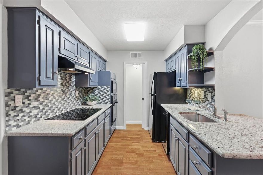 Tucked inside the gated Preston Hollow Condos at 5800 Royal Lane, this beautifully updated lower level 2-bedroom, 2-bath condo delivers the best kind of easy living thats private, polished, and close to everything.

Inside, real hardwood floors and fresh paint set a clean, warm tone from the start. The light-filled living room overlooks the quiet north courtyard, while the open dining area connects seamlessly to the kitchen with a convenient breakfast bar for a couple of stools.

The kitchen is a standout with granite countertops, glass cooktop, built-in wall oven with microwave above, a generous pantry, and thoughtful extras you’ll actually use, like a dedicated stackable washer dryer space, plus a built-in desk area with glass shelving for display or a work-from-home setup. Step outside to the patio and enjoy views of the pool.

Both bathrooms have been updated with timeless finishes and serious storage. The primary suite features a step-in closet plus an additional closet within the bathroom, complete with shelving and drawers. You’ll love the granite-topped vanity and the tiled tub shower combo with glass doors. The guest bath includes a tiled stand-alone shower and a wood vanity with plenty of storage. The second bedroom works beautifully as an office or guest room, offers a full-length walk-in closet with shelving, and has views toward the pool on the south side.

Enjoy your own covered parking space just out the door. This community feels like a private retreat with mature trees, gated access, 24-hour security, on-site management, and four pools for a quick dip or an all-day reset. When you’re ready to head out, Preston Royal shopping and nearby dining are just a short walk or drive away.

Bonus: the HOA dues offer exceptional value, covering all utilities including electricity, water, internet, streaming services, and more. This is lock-and-leave convenience without giving up comfort or style.