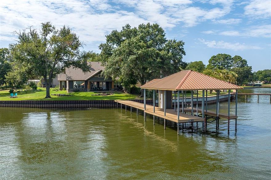 Sprawling Lake Retreat With Amazing Open Water Views & Over 300' Of Protected Shoreline! This custom 5 bedroom, 3 bath short term rental friendly home features a seamless open concept design with walls of windows offering unobstructed views of the lake. Elegant gourmet kitchen features an expansive island with granite countertops, stainless appliances, including double ovens, 5 burner gas cooktop, & an ice maker. Lakeside master suite with two walk-in closets & spa like bath that offers a soaking tub & large tiled shower. The additional guest bedrooms & baths are thoughtfully laid out in a split arrangement for optimal privacy & feature granite counters along with tiled shower-tub combo. Large covered patio that overlooks the lake & a great boat house complete with a cradle lift to secure your boat. The 42x60 shop stands ready to accommodate boat-RV-car storage or overnight guests. The shop-garage includes a separate 521 sq ft 1bdrm 1bth guest quarters equipped with a kitchen.