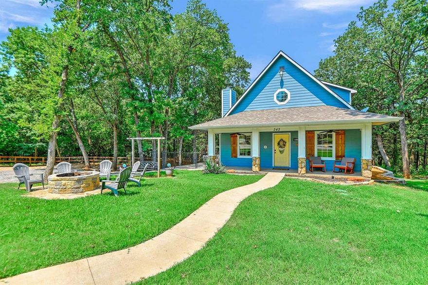Some places just feel like a deep breath the moment you arrive. This sky-blue craftsman cottage tucked into the trees on the tip of Preston Bend Peninsula is exactly that kind of place and ready to be yours. Set on half an acre with no HOA and backing up to corp land, 343 Plantation Ave is a rare find on one of the most coveted stretches of Lake Texoma. A short walk down a private trail leads straight to the sandy beach, no crowds, no chaos, just the lake and the sound of the water. The covered front porch and board-and-batten exterior set the tone from the moment you pull in. Inside, beadboard ceilings, a wood-burning fireplace, and abundant natural light make it feel like every day is a slow Saturday morning. The updated kitchen features granite countertops, a center island, and quality appliances. The primary suite is on the main level with a jetted garden tub, separate shower, and access to the relaxing back deck. Additional bedrooms upstairs have walk-in closets; perfect for guests and kids. Step out onto the second-floor deck of one upstairs bedroom and you're eye-level with the treetops, a quiet perch that makes the whole world feel a little slower. The other  is a true bunk room with double bunks, wood floors, and vaulted ceilings that sleep a crowd without anyone feeling cramped. Multiple outdoor living areas; a covered porch, deck, patio, upstairs balcony, and stone fire make entertaining effortless. And the workshop? 11-foot ceilings, garage door, electricity, and room for every lake toy in your arsenal PLUS room for games and hanging out!  Just minutes from Highport Marina, the Island Bar & Grill, Bay at the Lake, Tanglewood golf, and Eisenhower State Park. Lake Texoma is known as the Playground of the Southwest, and from this address, the playground is your backyard!