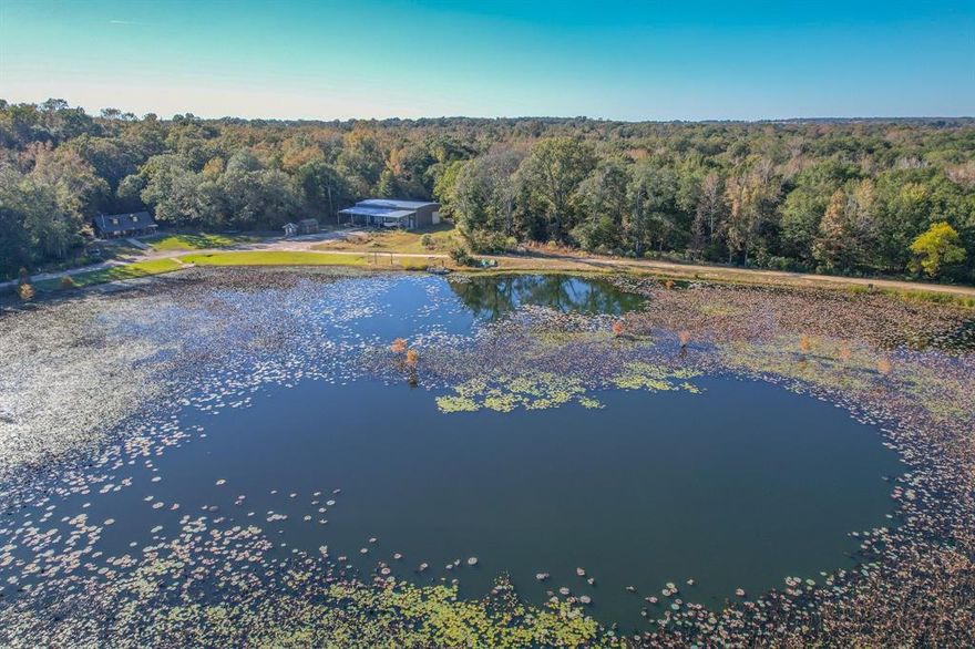 Set on 100 scenic acres, this remarkable property offers the perfect blend of recreation, relaxation, and natural beauty. The centerpiece is a stunning 13-acre spring-fed lake with deep holes, stocked with bass and frequented by wintering waterfowl — ideal for fishing, kayaking, or simply enjoying the view from the cabin’s porch.
The land’s unique shape is a true advantage, creating a sense of space and privacy that makes the property feel even larger than its acreage suggests. A well-maintained trail system winds through a mix of hardwood timber, open pasture, and lakeside areas, providing easy access for hunting, hiking, and ATV riding.
The charming 2-bedroom, 1-bath cabin features an open floor plan with a loft and a front porch overlooking the lake — a perfect spot for morning coffee or an evening sunset. Nearby, a large, well-built metal building adds incredible versatility. It includes multiple automatic bay doors, a concrete floor, HVAC, and lighting, plus an expansive covered overhang for outdoor storage. Inside, a finished 1-bedroom, 1-bath apartment with a full kitchen offers comfortable guest or caretaker quarters. An additional upstairs loft space is ready to finish out as a man cave, second apartment, or storage area.
With road access on both ends, a great mix of timber and open ground, and a lake that’s second to none, this property is a true recreational retreat and a must-see opportunity in a desirable area.

13-acre spring-fed lake with deep water, planted cypress, stocked with bass, and wintering waterfowl
Additional large pond with planted cypress 
2BR 1BA cabin with open floor plan, loft, and porch overlooking the lake
Large insulated metal building with concrete floor, HVAC, lighting, and multiple automatic doors
Includes a 1BR 1BA finished apartment with kitchen inside the shop
Road access from both ends of the property
Boundaries in yellow are approximate and to be verified by survey