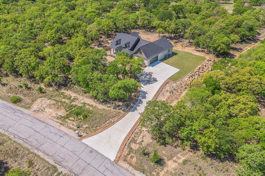 Tucked among mature trees in the exclusive gated lakeside community of North Star Pointe, this stunning NEW CONSTRUCTION home blends timeless architecture with peaceful country charm. Sitting on 1.24 ac lot and designed with an open, spacious layout, it’s perfect for both everyday living and entertaining, with abundant windows that flood the home with natural light and showcase the serene surroundings. The living room features a vaulted ceiling, a beautiful brick fireplace, and custom built-in cabinetry. Thoughtful upgrades throughout include luxury vinyl plank flooring, designer lighting and long blade fans, and a stylish wet bar complete with an ice machine. The kitchen is a true centerpiece, offering granite countertops, a farmhouse sink, stainless steel appliances, a large eat-in island, two-tone cabinetry, and an oversized pantry with exceptional storage. Three bedrooms are conveniently located on the main level and thoughtfully split for privacy. The primary suite is a relaxing retreat with double vanities, upgraded finishes, a freestanding soaking tub, separate shower, and a spacious walk-in closet with direct access to the laundry room. In additon there is a half bath tucked away for guest convenience. Upstairs, you’ll find a versatile bonus space ideal for a second living area or game room, along with another bedroom or 2nd Living area with full bath, and an additional bonus room perfect for a bunk room or home office. Enjoy peaceful mornings and evening sunsets from the expansive elevated front porch or covered back patio, surrounded by nature and wildlife. Residents of North Star Pointe enjoy access to premium amenities including the community pool, pickleball court, and private boat ramp with dock—bringing the best of lakeside living right to your doorstep.
If you’re searching for a quiet escape with a Hill Country feel, this home delivers.