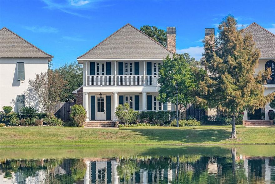 Welcome to this exquisite home overlooking beautiful Windrush Lake, offering one of the most desirable views in Provenance. Enjoy a wonderful, connected way of life with neighborhood favorites just steps away, including the bank, post office, dining, medical offices, clubhouse, community pool, and parks. Relax on the charming covered front porch or the upstairs balcony, both with serene lake views—perfect for morning coffee or watching the New Year’s fireworks reflected over the water. The inviting living room features built-ins, a cozy fireplace, and large picture windows framing the lake. Elegant crown molding, new wood flooring in the formal dining room and primary suite, and abundant natural light enhance the warmth and sophistication of this classic Acadian-style home. The chef’s kitchen is a true delight with a spacious island, granite countertops, abundant cabinetry, stainless steel appliances including double ovens, and a built-in desk area ideal for work or meal prep. The formal dining room offers a welcoming setting for entertaining guests and hosting memorable gatherings. A well-appointed downstairs powder room adds convenience and style for visitors. The luxurious downstairs primary suite is a peaceful retreat with plantation shutters, dual walk-in closets, and a spa-like bath featuring a jetted tub and separate shower. Upstairs, two spacious bedrooms with high-end draperies share a full bathroom, creating a comfortable and stylish space for family or guests. Additional highlights include a great utility room with storage and sink, an attached two-car garage, and a spacious fully fenced rear yard. Every morning, herons perch along the water’s edge, completing the tranquil lakeside atmosphere of this exceptional Provenance home.