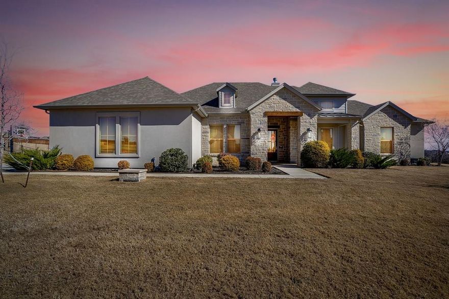 Experience exceptional indoor–outdoor living in this beautifully appointed single-story home, perfectly situated on over an acre within the highly sought-after Aledo ISD. Designed for both comfort and functionality, this spacious four-bedroom floor plan includes a dedicated office and a large game room, offering flexible spaces for work, play, and everyday living.  The inviting main living area showcases rich wood beams and a dramatic floor-to-ceiling stone fireplace, creating a stunning focal point at the heart of the home. The chef’s kitchen features a large quartz-topped island, abundant cabinetry, and double ovens—ideal for cooking, hosting, and entertaining.  The private primary suite is thoughtfully separated from the secondary bedrooms and offers a serene retreat with a spa-like ensuite including a walkthrough shower, separate soaking tub, and dual vanities. A generously sized primary closet provides exceptional storage and conveniently connects to the utility room, which features ample cabinetry and a sink for added convenience. Two secondary bedrooms share a convenient Jack-and-Jill bath, while the additional bedroom and living spaces are designed with versatility in mind.  Sliding glass doors open to an impressive outdoor oasis with a covered patio and elegant travertine decking. The resort-style backyard showcases a brand-new pool with a tanning ledge, in-water table, and spa, along with a fully equipped outdoor kitchen complete with a built-in grill and refrigerator—perfect for entertaining year-round.