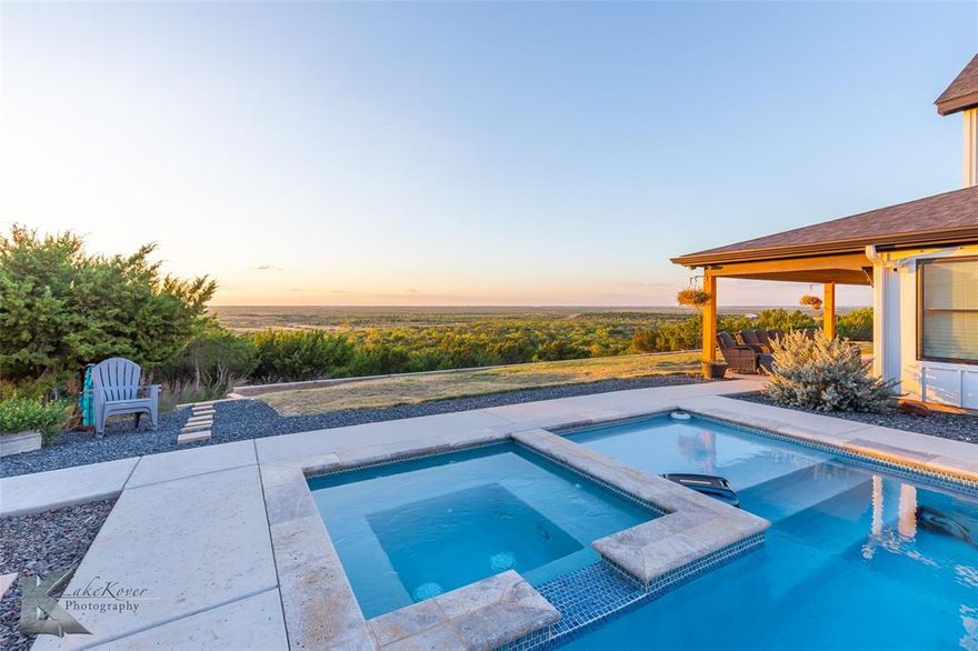 Welcome to your private West Texas retreat—where comfort, craftsmanship, and breathtaking views come together on more than 38 stunning acres. Built in 2022, this 2,824 sq ft home offers peaceful privacy while still being just minutes from downtown Abilene. Inside, an inviting open floorplan centers around a spacious living area with soaring vaulted tongue-and-groove ceilings and a striking double-sided fireplace that warms both the living room and the serene primary suite. Foam insulation, energy-efficient systems, and no HOA provide year-round comfort and long-term value. The kitchen is designed to impress with a large island, custom cabinetry, subway tile backsplash, and stainless steel appliances including a gas range, dishwasher, and microwave drawer. A massive walk-in pantry with appliance shelving offers exceptional storage, while the farmhouse sink overlooks the stunning surrounding landscape. Beneath the stairs, a charming dry bar with wine fridge and shelving creates the perfect space for entertaining. An open staircase leads to a bright loft bonus room offering flexible space for a game room, office, or additional lounge area. The primary suite features direct porch access and a spa-like bath with dual sinks, a soaking tub, tiled walk-in shower, and generous storage. Two spacious guest bedrooms provide comfort for family or visitors, including one with porch access and panoramic views. Outside, the property truly shines. A resort-style pool and spa anchor the backyard, framed by the home on one side and a versatile 1,500 sq ft metal shop on the other. The shop includes electricity, a storage loft, and a large covered overhang facing the pool—perfect for shaded lounging and gatherings. Inside, a finished man cave opens directly to the pool area for seamless indoor-outdoor entertaining. With ample parking, private trails, hunting opportunities, and unforgettable sunset views, this remarkable property captures the freedom and beauty of West Texas living.