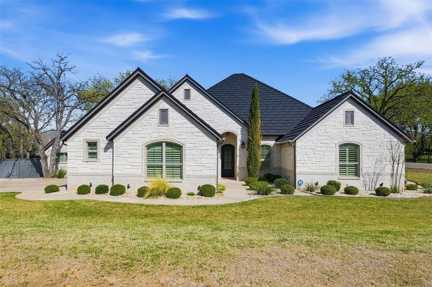 EXCEPTIONALLY NICE 4-bedroom, 2-bath custom-built Hopper home, perfectly situated in the highly sought-after Pecan Plantation golfing community.  Spacious floor plan boasts premium finishes throughout -- crown molding, hardwood floors, travertine, 8’ doors, central vac, and oversized closets.  Plantation shutters on all windows, including garage and outbuilding; exterior uplighting. Gourmet kitchen is equipped with double ovens, KitchenAid appliances, and a 5-burner gas cooktop. Breakfast nook & bar. Focal point of oversized living room is a handsome stone, gas fireplace. Ensuite for Primary bedroom has his & hers vanities, garden tub, separate shower, and Toto Washlet toilet. Handy pull down rods in Primary closet that connects to laundry room. 4th bedroom would make a great office. 27 X 17 upstairs Bonus room. This meticulously maintained property features an oversized garage with epoxy floors, LiftMaster garage door opener and a versatile outbuilding, offering both convenience and extra storage. Screened in back patio has tile floors, outlet for TV & extended concrete pad. Installed in 2024: Tek System metal roof with lifetime warranty, complemented by new gutters and Lennox Elite HVAC with an electronic air purification system. 7-zone sprinkler system. Trex privacy fence in encompasses a pretty landscaped backyard. This home blends luxury, functionality, and prime location—don’t miss the chance to own a piece of Pecan Plantation’s finest! Close to Pecan amenities, including Marina, clubhouse, golf courses, stables, tennis, pickleball, community pool, Fire & EMS and more. Just minutes from Lake Granbury, the Hood County Square, offering quaint shops, restaurants and weekend activities. An hour from Ft. Worth.