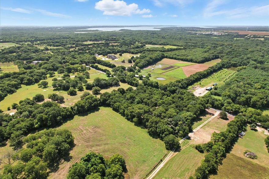 SUPER LOCATION WITH UNLIMITED POTENTIAL! Discover 3.65 picturesque acres in the McKinney ETJ, tucked away in a quiet setting yet convenient to McKinney, Fairview, and Lowry Crossing in highly desirable Collin County. Located outside city limits with no known deed restrictions, this property offers options for a custom home, private estate, small-scale development, or long-term investment hold (buyer to verify all use possibilities). The land feels like a secluded, wooded retreat with mature Oak, Elm, and Black Walnut trees and boasts approximately 400+ feet of county road frontage, providing an impressive approach and multiple siting options. Water, electric, and septic are already on site, and a well-maintained manufactured home with porches and carport is in place, positioned to overlook the beautiful natural landscape. Enjoy the rare combination of privacy and accessibility—just minutes to Stacy Road, Hwy 75, and historic downtown McKinney—while benefiting from no HOA and no city taxes. Bring your builder, your plans, or your investment vision and make this unique North Texas property your own.