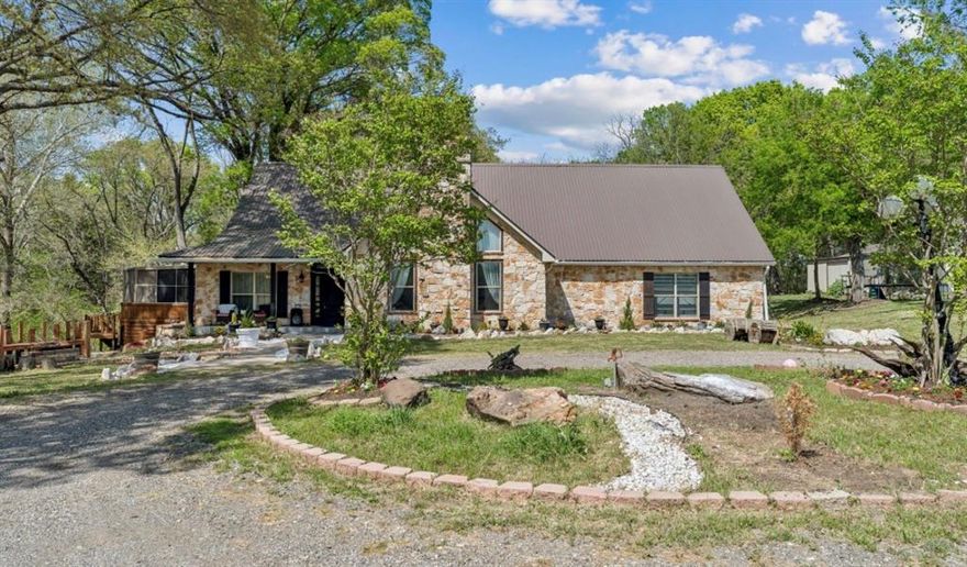 Welcome to your private country retreat- where charm, character and modern comfort come together on 12 plus stunning acres surrounded by mature trees and open pasture. A scenic, winding driveway with beautiful wood fencing sets the tone as you arrive at this gorgeous stone-accented one-story home, offering timeless curb appeal and peaceful seclusion. Step inside to an inviting open layout featuring soaring vaulted ceilings with exposed beams, rich hardwood floors, and a floor to ceiling stone fireplace that creates a warm and impressive focal point. Natural light pours through oversized windows, bringing the beauty of the outdoor in. The fully updated kitchen is a dream, featuring custom cabinetry, sleek countertops, stainless steel appliances, and spacious island all opening seamlessly to a cozy breakfast nook with scenic view. Just of the kitchen enjoy a truly unique feature - an enclosed outdoor living space with wood beams, ambient lighting, and plenty of room for dining and entertaining year around. The Primary suite offers a relaxing retreat, with generous space with amazing master bath with 2 stylish vanities, separate shower and bathtub. Additional bedrooms provide flexibility for quests and office. Outdoor features you will love includes 12 plus acres of beautiful useful land, charming fire pit area in front of the house perfect for gathering under Texas sky, mature trees for shade and privacy, workshop barn ideal for equipment or storage, expansive open pasture perfect for animals, long private driveway with fencing which added character, 3 car garage, and much more. This property offers the ideal blend of peaceful and comfortable ranch living all within convenient reach of nearby highways, shopping and dining. A rare opportunity to own your very own slice of Texas paradise with having the benefit of AG exemption.